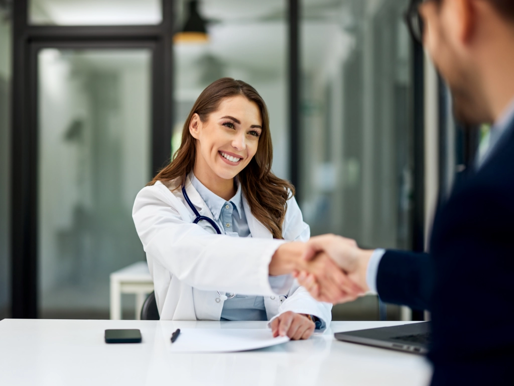 Ärztin begrüßt einen Bewerber mit Handschlag in einer modernen Praxis – neue Chancen über Ärztevermittlung